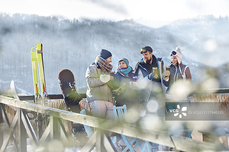 滑雪者朋友在阳光明媚的阳台上聊天和喝鸡尾酒图片素材