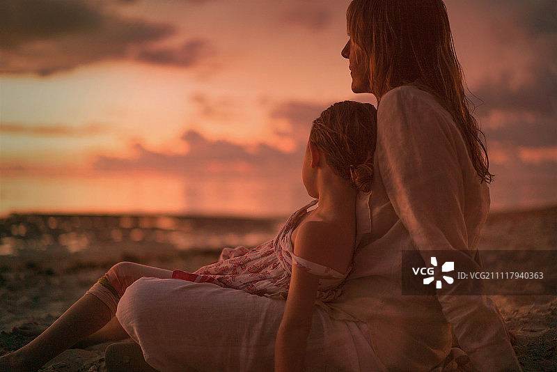 宁静的黄昏海滩上，母女放松身心图片素材