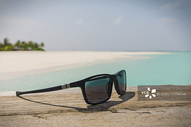 阳光明媚的热带海滩上的太阳镜特写图片素材