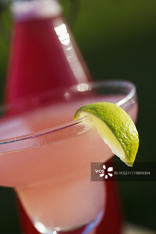 鸡尾酒杯中粉色饮品特写，饰以青柠片图片素材