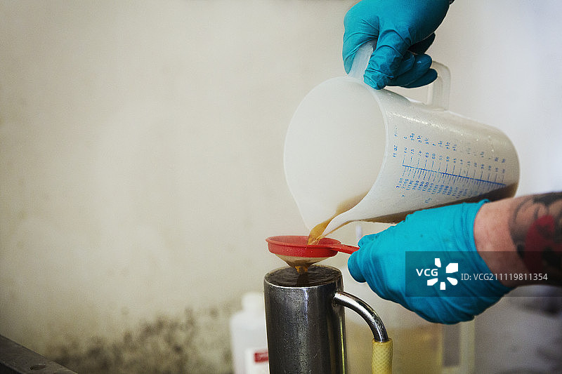 啤酒厂戴蓝色乳胶手套的人倾倒液体图片素材