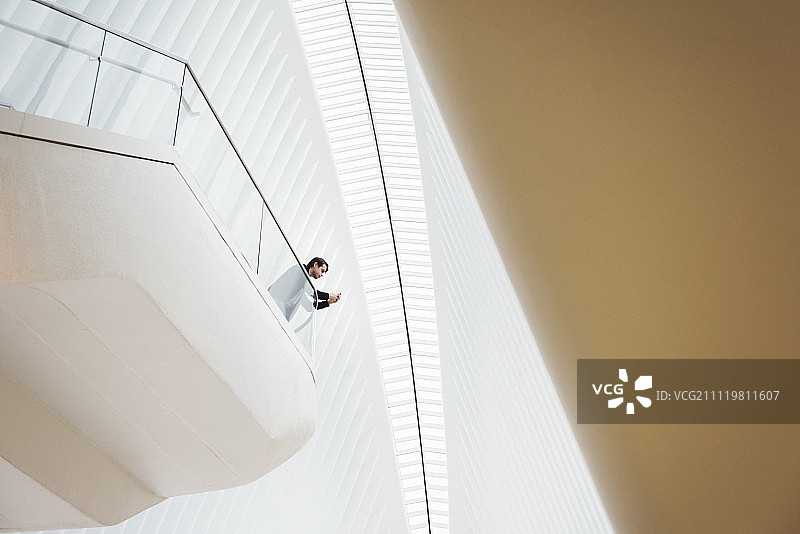 Oculus大楼阳台上看手机的男人仰视视角图片素材