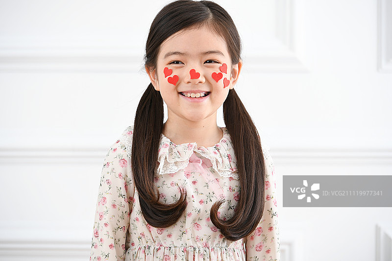 女孩在脸上贴心形贴纸图片素材