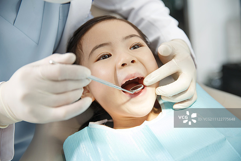 男牙医在为小女孩检查牙齿图片素材