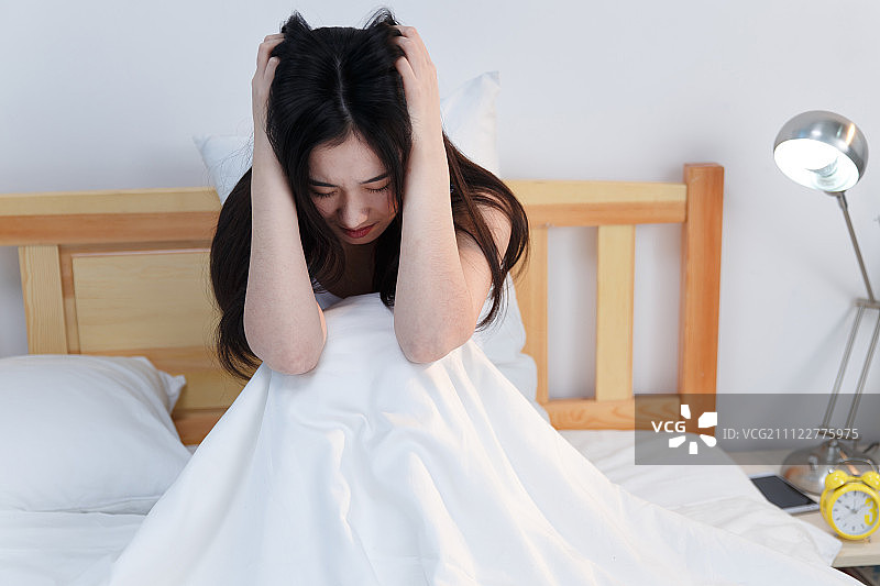 情绪低落的青年女人坐在卧室的床上图片素材