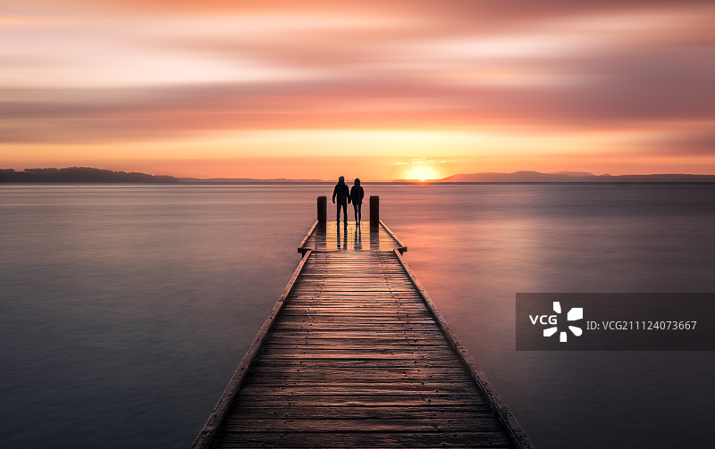 栈桥上看夕阳的情侣图片素材
