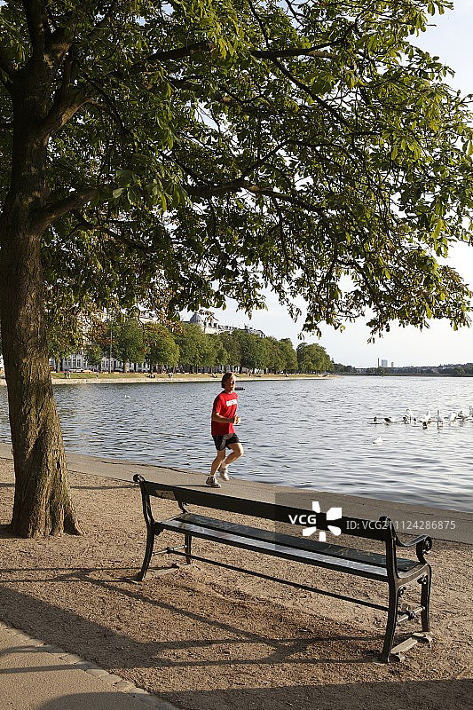 男子在丹麦哥本哈根的公园水岸旁慢跑图片素材