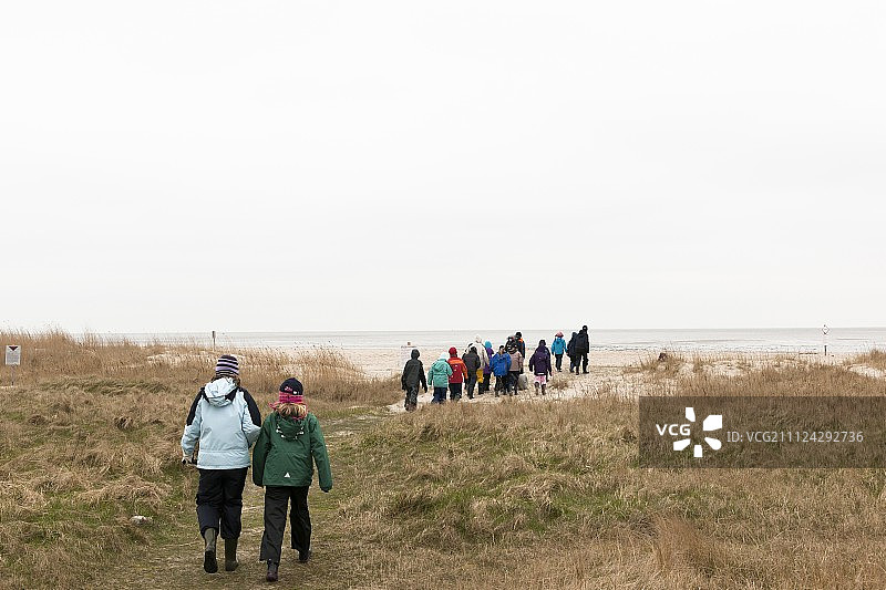 在德国瓦登海滩上，孩子们和看护人在一起图片素材