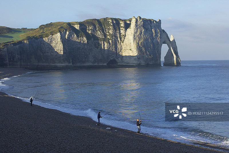 三名男子在岩石海岸附近的海滩上钓鱼图片素材