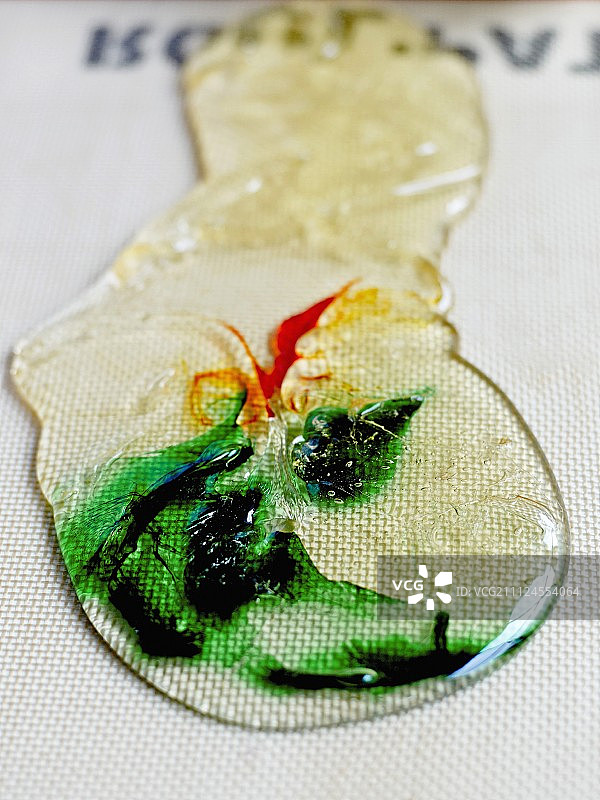 用手指将糖膏的边缘向中心折叠，并将绿色和原色糖膏分离图片素材