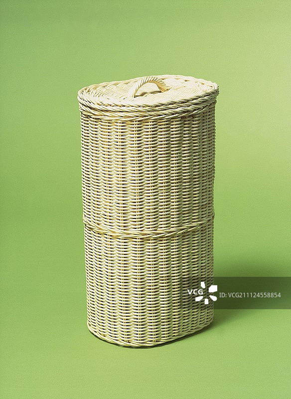绿色背景上的浅棕色柳条洗衣篮图片素材