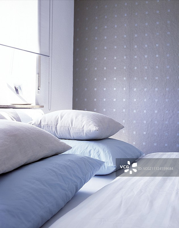 双人床上蓝色和奶油色枕头的特写，背景是纺织壁纸图片素材