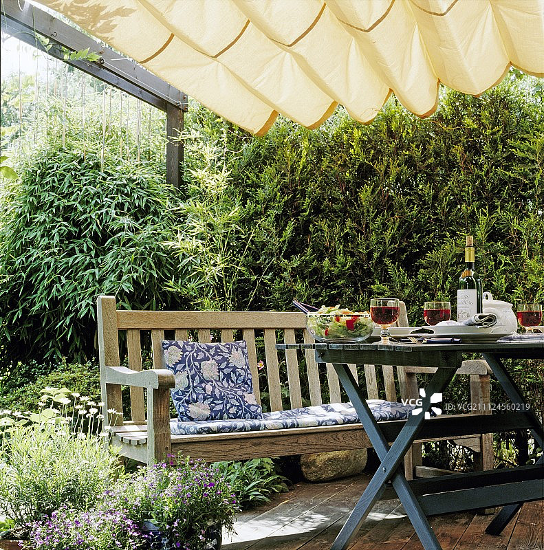 花园凉棚下带长椅和垫子的桌子图片素材