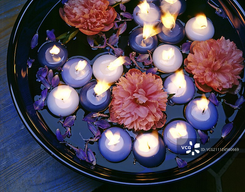 玻璃碗中盛放的蓝白色漂浮蜡烛与牡丹花图片素材