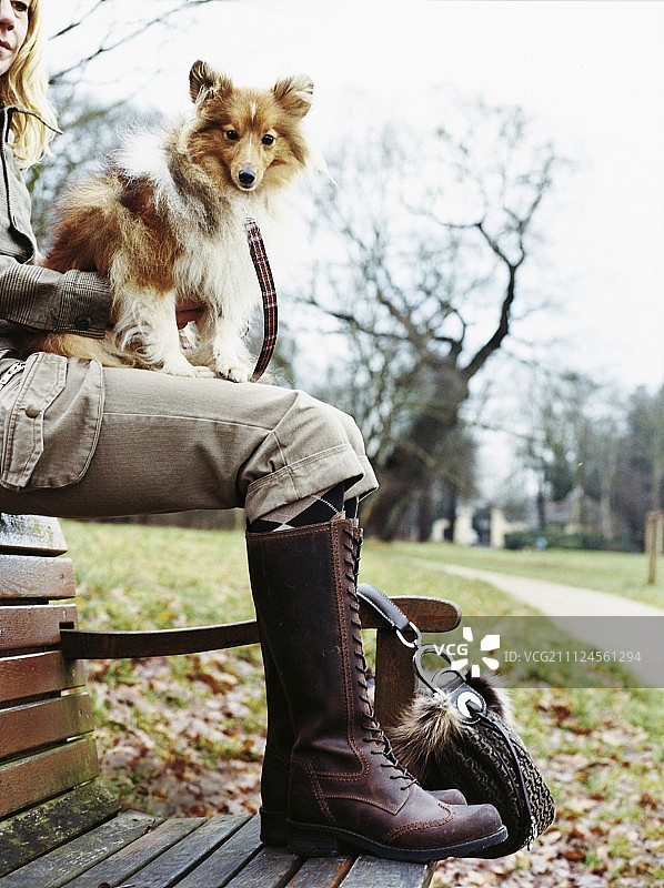 近距离拍摄女人坐在公园里，狗在腿上图片素材