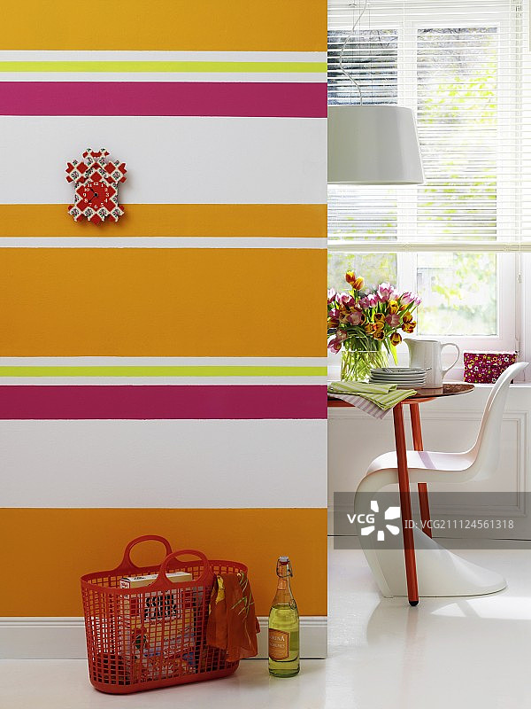 彩色条纹墙前的红色篮子和餐厅一角图片素材