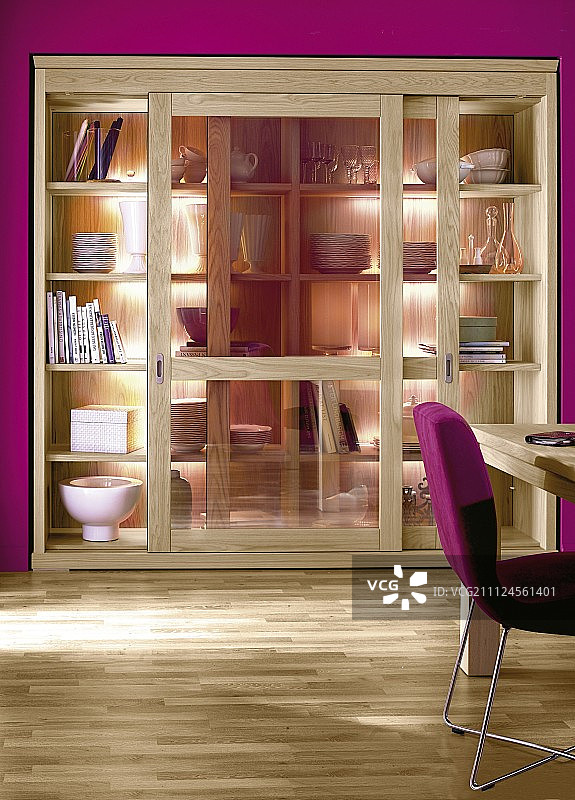 粉红色墙壁和侧面椅子上的滑动玻璃门橡木柜图片素材