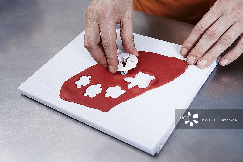 用饼干切割器切割花卉图案杏仁糖的人图片素材