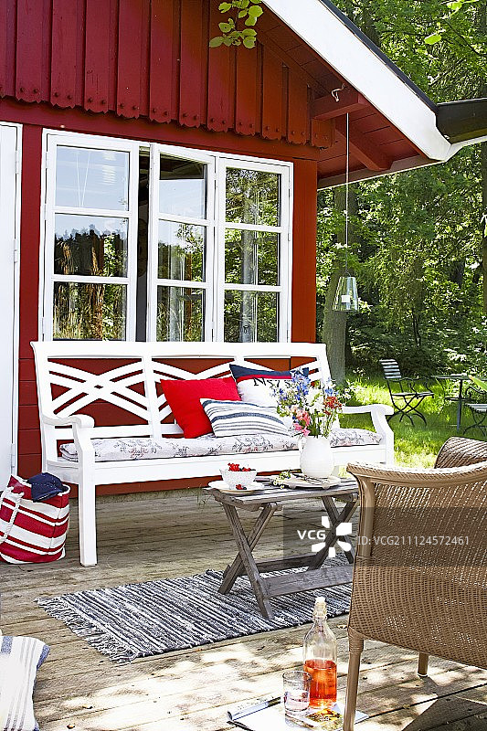 庭院中带花园长椅和柳条椅的红色花园房屋图片素材