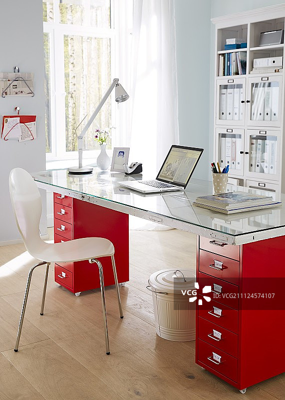 红色办公桌配台灯、笔记本电脑和椅子图片素材