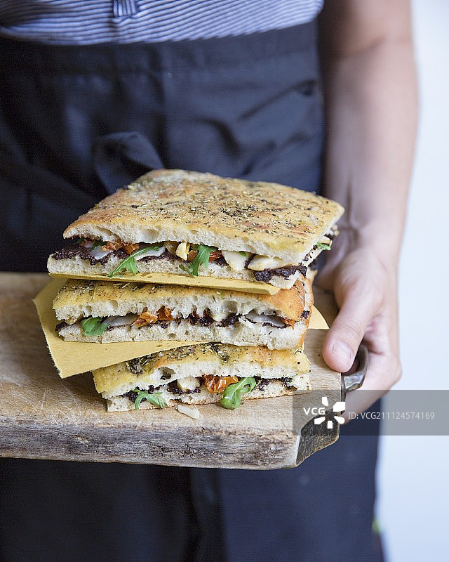 黑橄榄酱、腌朝鲜蓟、番茄干、芝麻菜和帕尔马干酪佛卡夏三明治图片素材