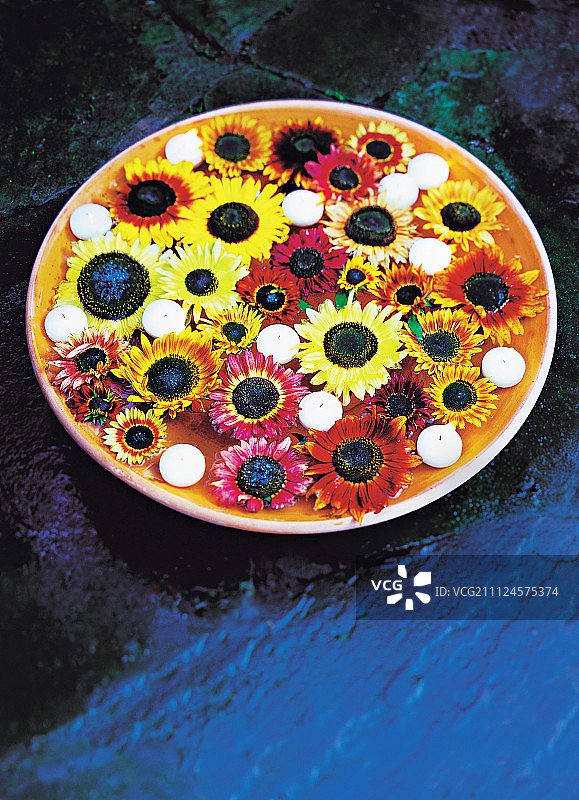 漂浮在水中的瓦罐里装饰着新鲜的向日葵和蜡烛图片素材