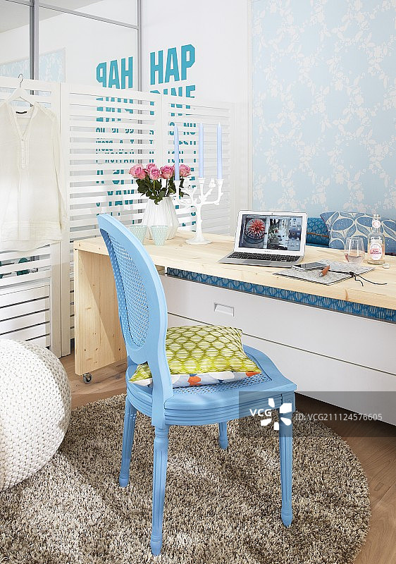床前用作书桌的带轮木桌和蓝色编织椅图片素材