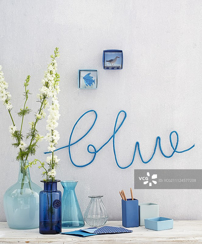 蓝色墙壁前的蓝色花瓶图片素材