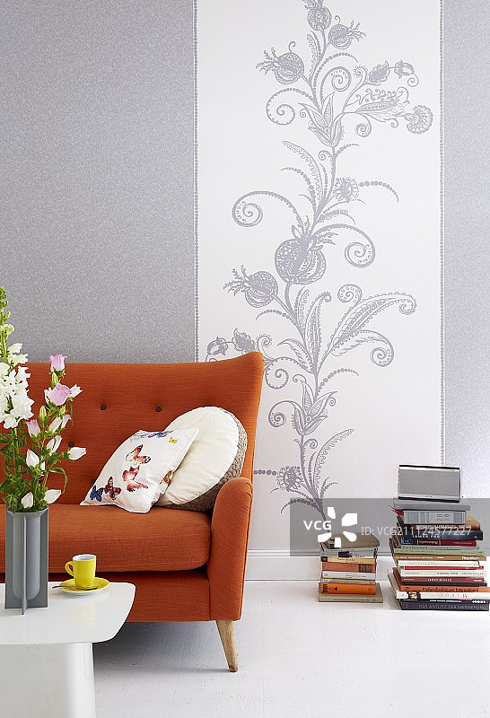 以灰色半实心图案和灰白色藤蔓图案壁纸为背景的橙色沙发图片素材