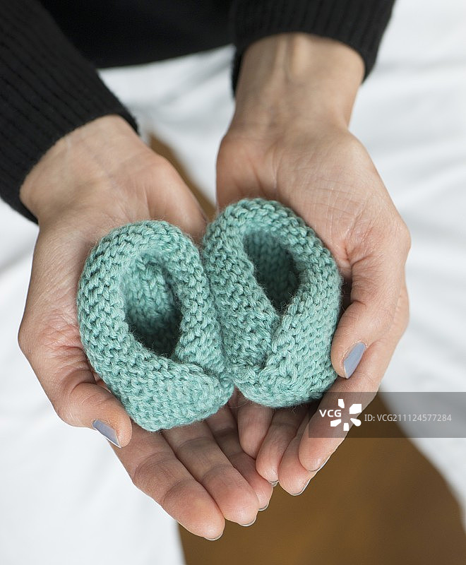女人拿着钩针编织的婴儿鞋图片素材