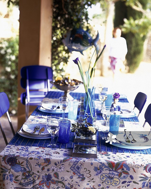铺着蓝色桌布、摆放着餐具和花瓶的桌子图片素材