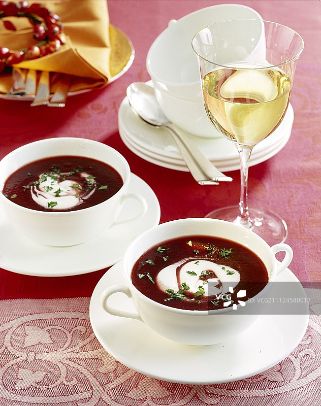 红甜菜汤配辣根，用奶油装饰在桌子上，旁边放一杯白葡萄酒图片素材