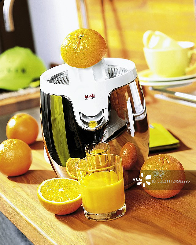 木桌上的橙汁榨汁机、橙子和橙汁图片素材