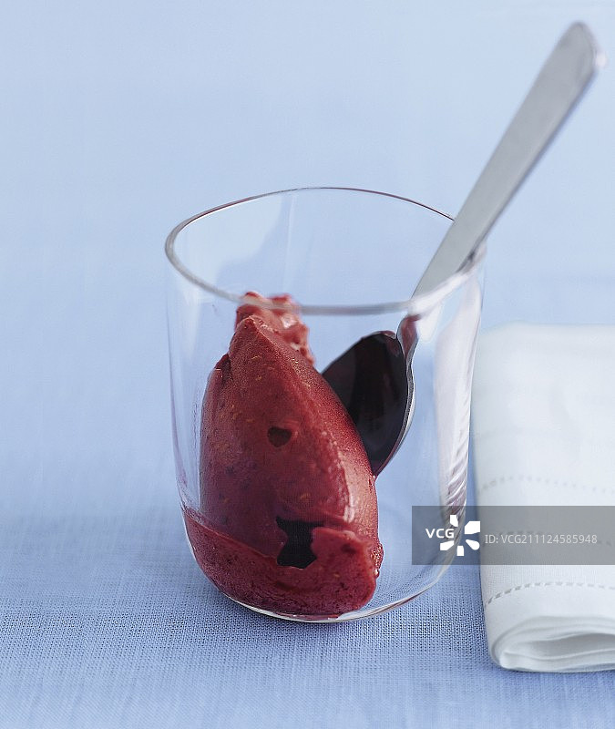 蓝色背景下的玻璃杯覆盆子与勺子图片素材