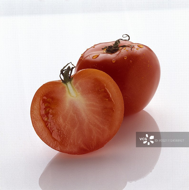 白色背景上的一个完整和一个切片的番茄图片素材