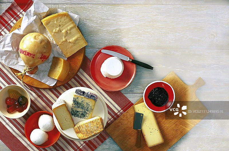 木制表面上带有刀的各种意大利奶酪和芥末水果图片素材
