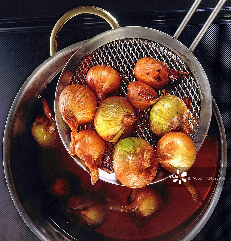 用滤网从锅中捞出煮熟的青葱，顶视图图片素材