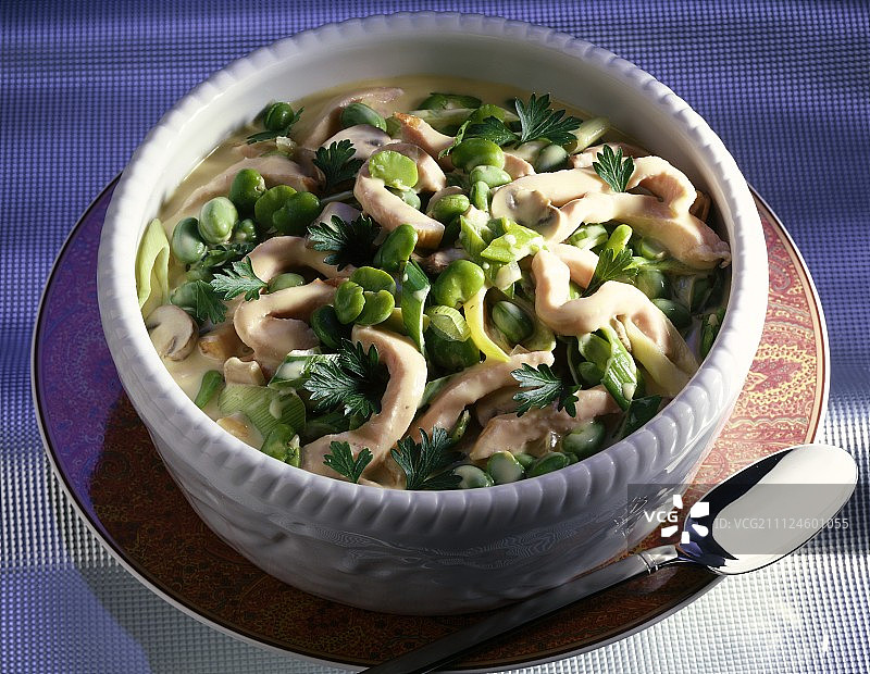 盘中盛有猪肉蔬菜杂烩（含蚕豆、韭葱、蘑菇和欧芹）图片素材