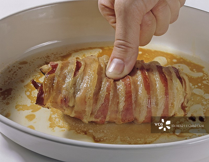 在餐盘中，手在野鸡胸肉上施加拇指压力的特写图片素材