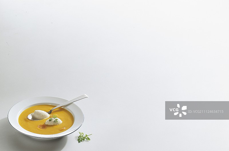 白色背景下碗里的胡萝卜汤配熏鱼慕斯和欧芹图片素材