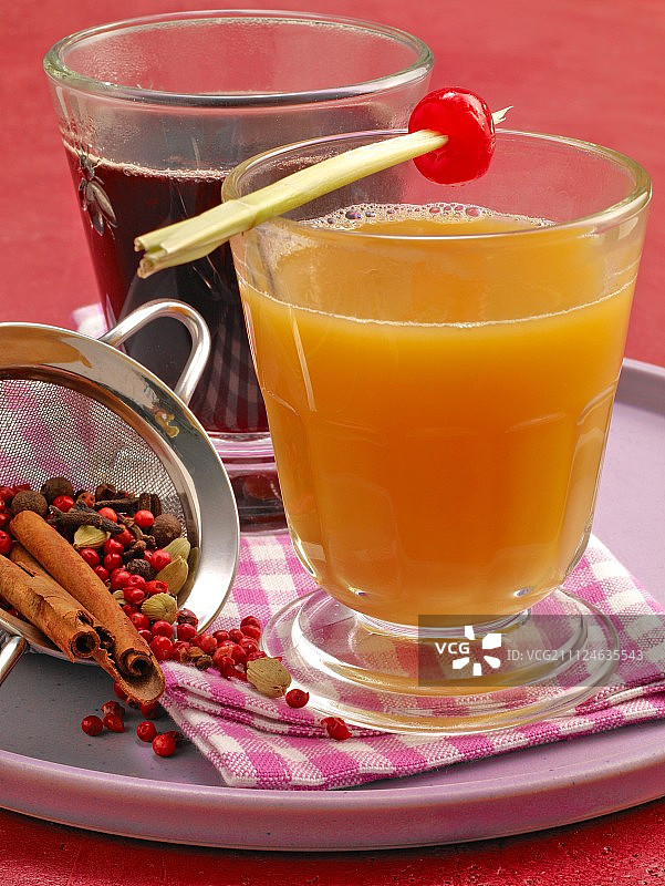 玻璃杯中的香辣接骨木潘趣酒和菠萝潘趣酒，带筛子里的胡椒图片素材