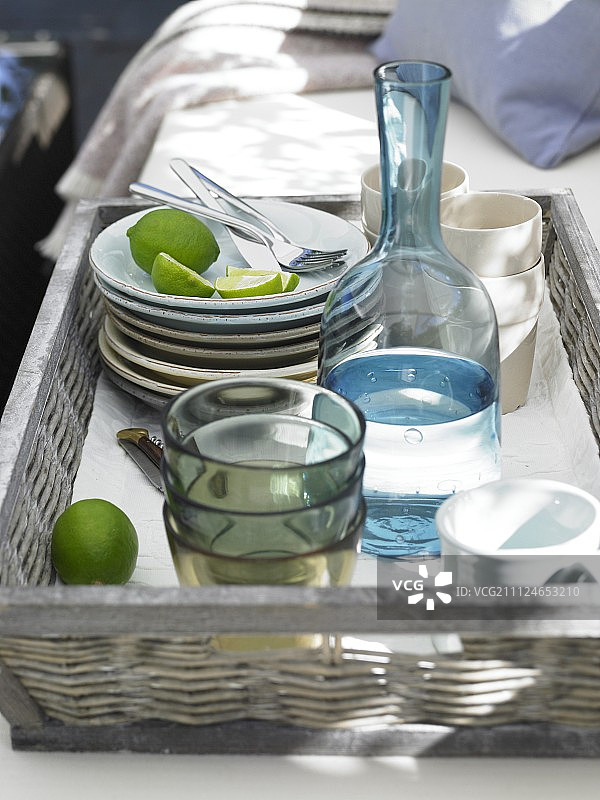 柳条托盘中的盘子、玻璃杯和醒酒器图片素材