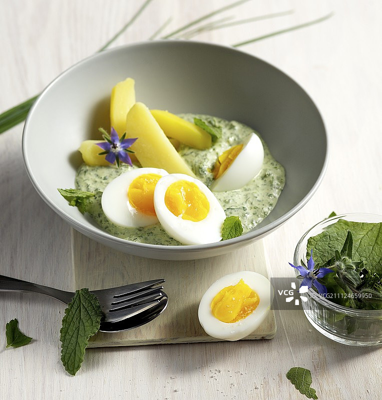 碗里有半个鸡蛋和煮土豆配绿色酱汁图片素材