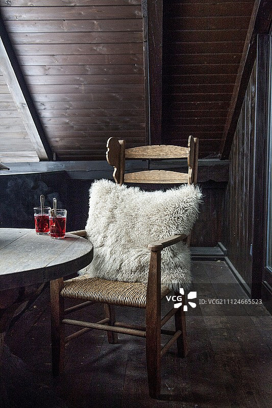 阳台上带有毛皮枕头和木桌上饮料的木椅图片素材