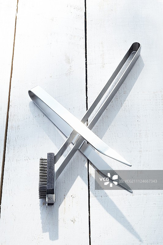 木地板上的不锈钢钳和烧烤刷图片素材