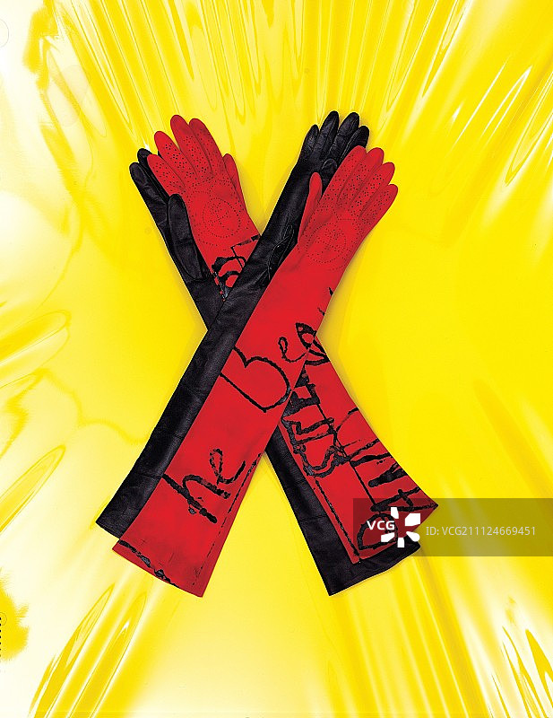 黄色背景上的红色和黑色长款皮手套图片素材