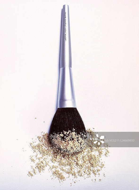 白色背景下的银色化妆刷和化妆粉图片素材