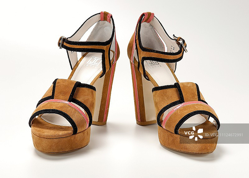 白色背景上的一双棕色麂皮凉鞋图片素材