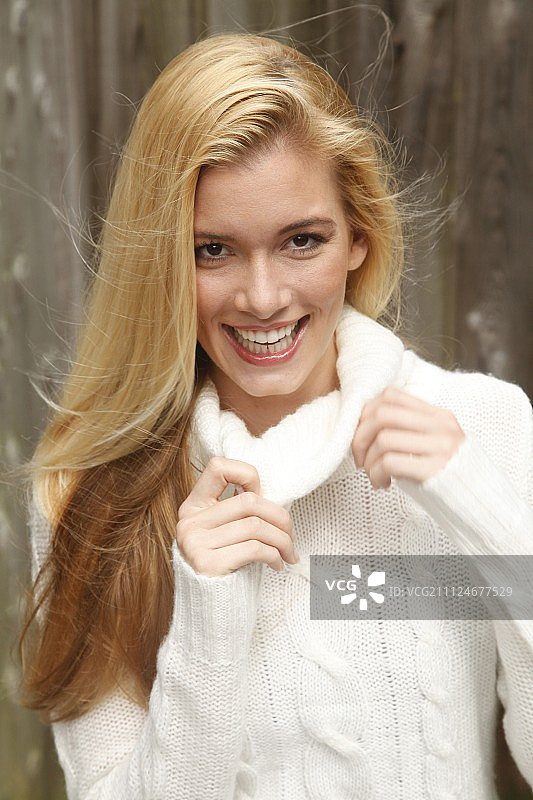 美丽的金色头发女子肖像，穿着白色高领毛衣，微笑图片素材