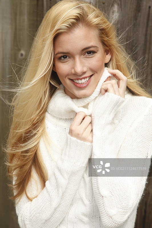 美丽的金色头发女子肖像，穿着白色高领毛衣，微笑图片素材